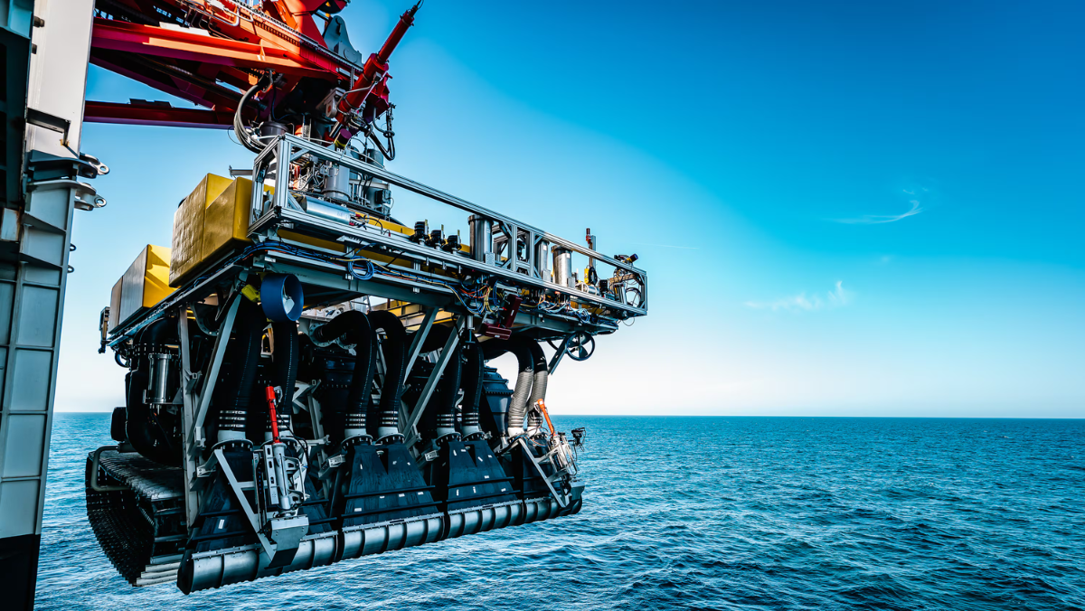 Deep-sea mining vehicle suspended over open ocean, showing advanced subsea machinery and exploration equipment.