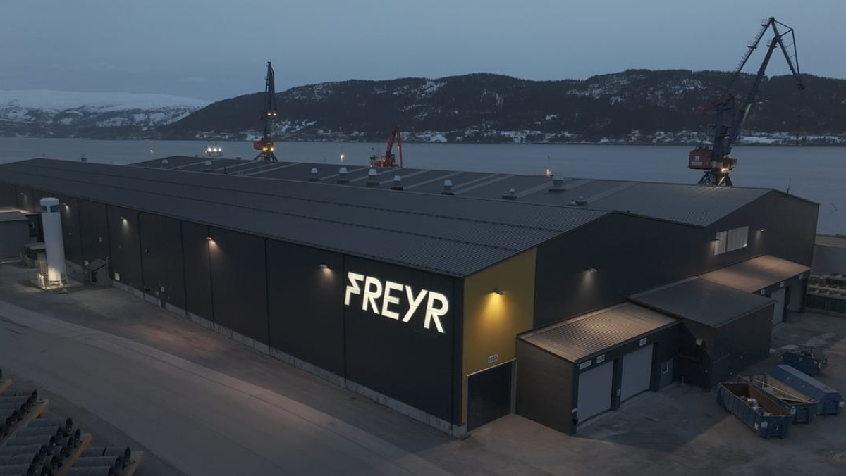 Freyr Battery industrial facility at dusk near waterfront shipping cranes