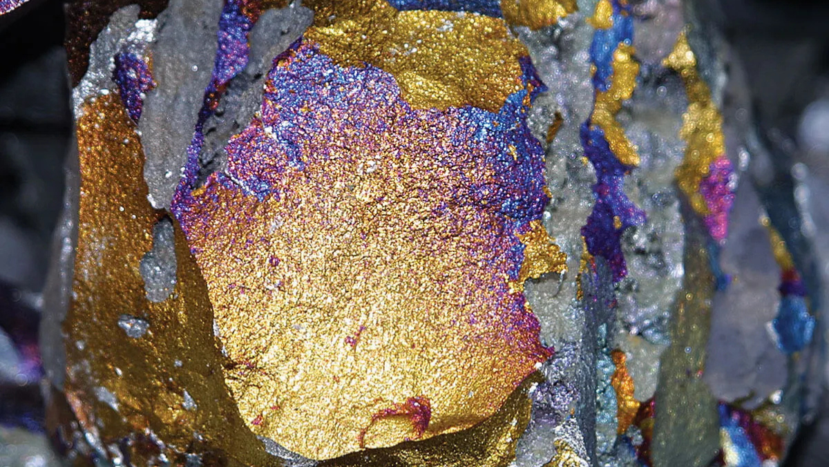 Close-up of colorful metallic mineral ore with gold, blue and purple tones