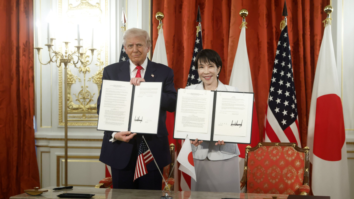 Japan and US officials hold signed documents at a bilateral signing event