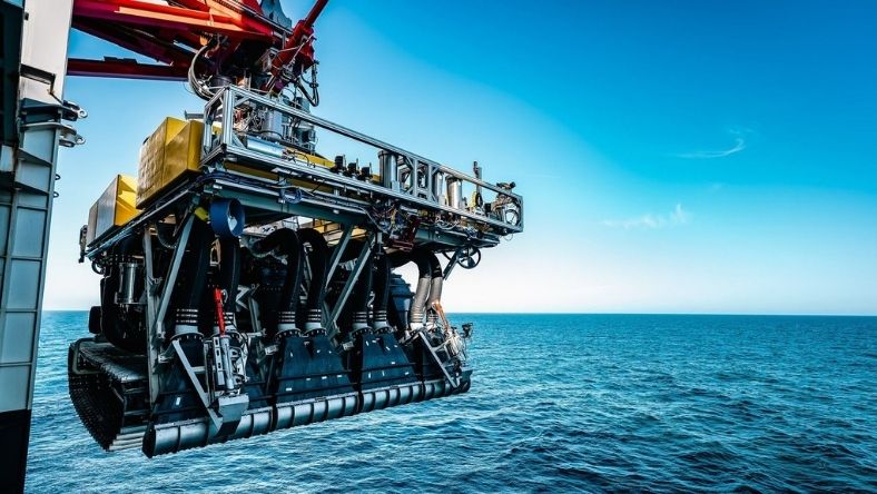 Subsea robotic mining vehicle suspended above ocean surface